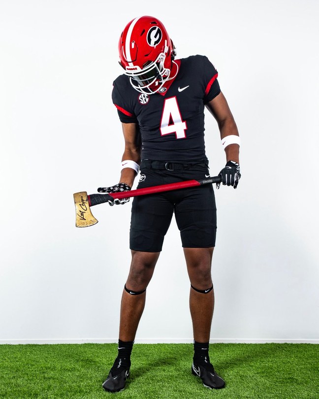 Jaxon Dollar in a Georgia Bulldogs uniform during a photoshoot after his commitment, holding a Georgia axe.